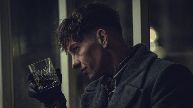 Barry Keoghan as Erasmus holding a glass of whiskey in Peaky Blinders: The Immortal Man