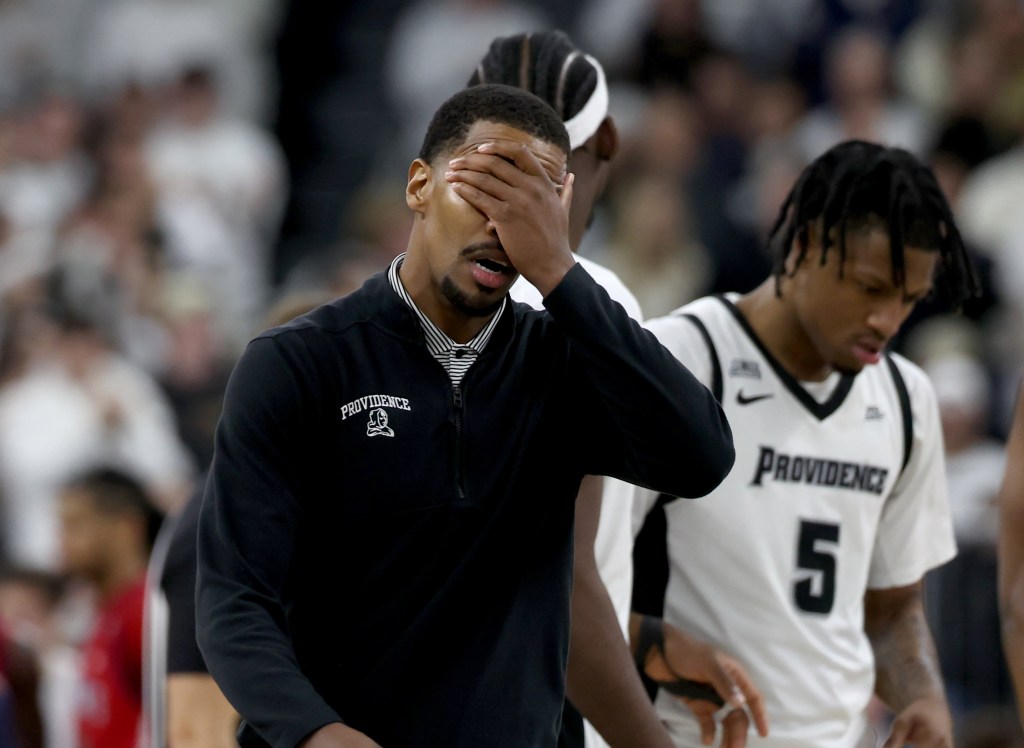 Providence head coach Kim English reacting with his hand over his face after a foul call during a basketball game.