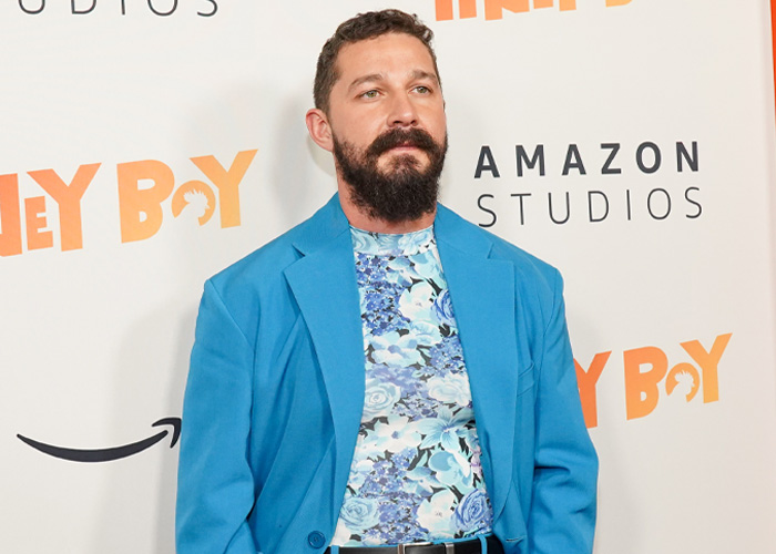 Shia LaBeouf at a red carpet event wearing a blue blazer and floral shirt, discussing mental health and Mardi Gras arrest.