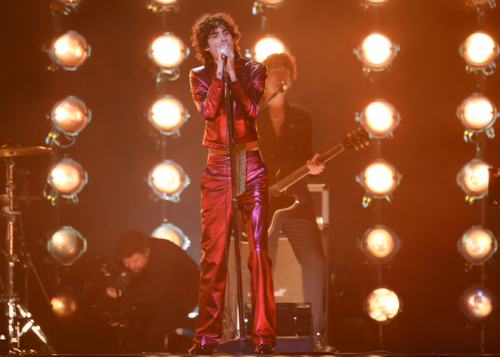 Singer performing on stage amid chaos at Brit Awards with bright lights and musicians in the background during viral moment.