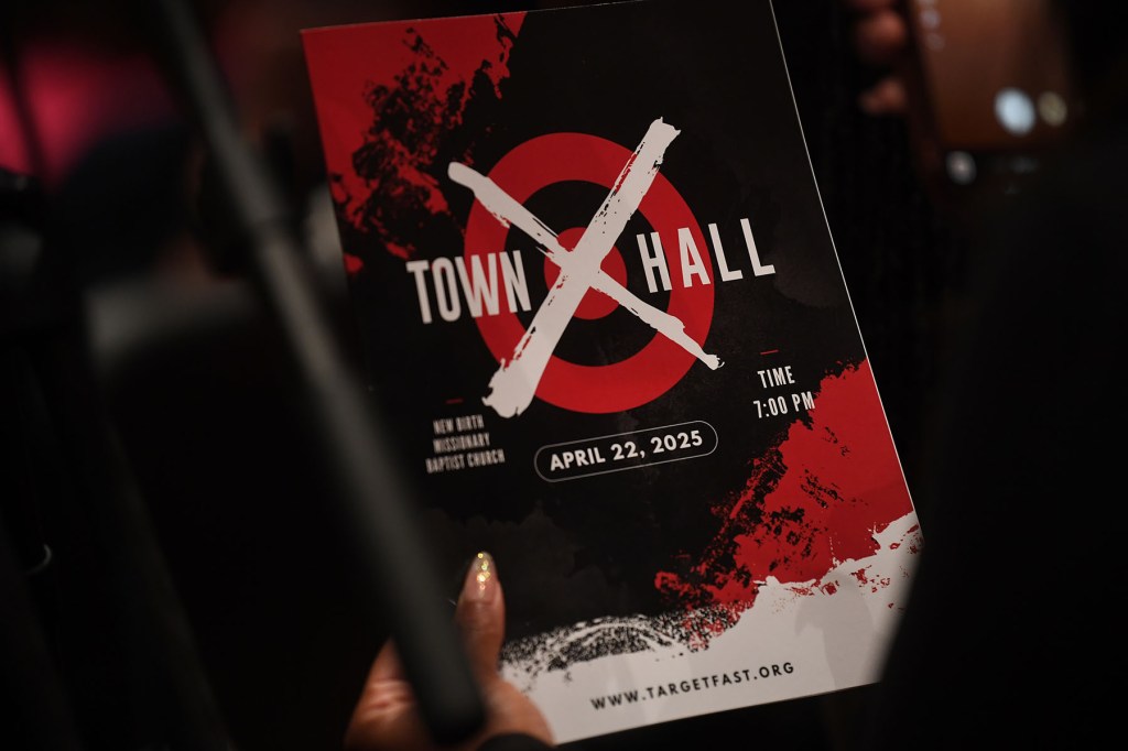 A person holds a program booklet reading “Town Hall” with a red target graphic during the Target Fast meeting.