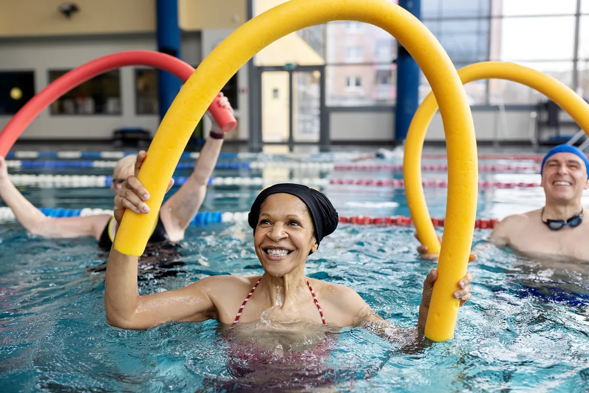 woman exercising in a pool with a pool noodle