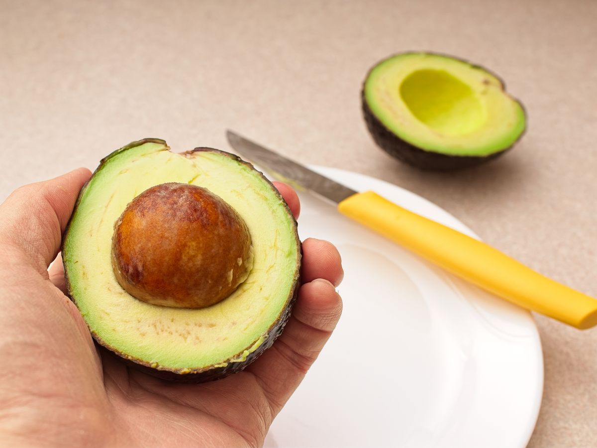 Ripe succulent avocado being prepared in kitchen. Avocadoes are a superfood containing high amounts of nutrition and healthy fats.