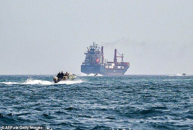 A boat approaches the St Kitts and Nevis-flagged container ship Marsa Victory while cruising in the waters of the Strait of Hormuz off the coast of Khasab in Oman's northern Musandam peninsula on June 25