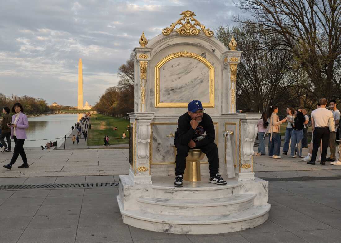 A man poses for photograph with a gold-painted, faux-marble toilet sculpture titled "A Throne Fit For a King," installed near the Lincoln Memorial. The statue, depicting an elaborate toilet throne, appears to mock President Trump's renovation of the bathroom attached to the Lincoln Bedroom a project that drew criticism for taking place during a government shutdown.
