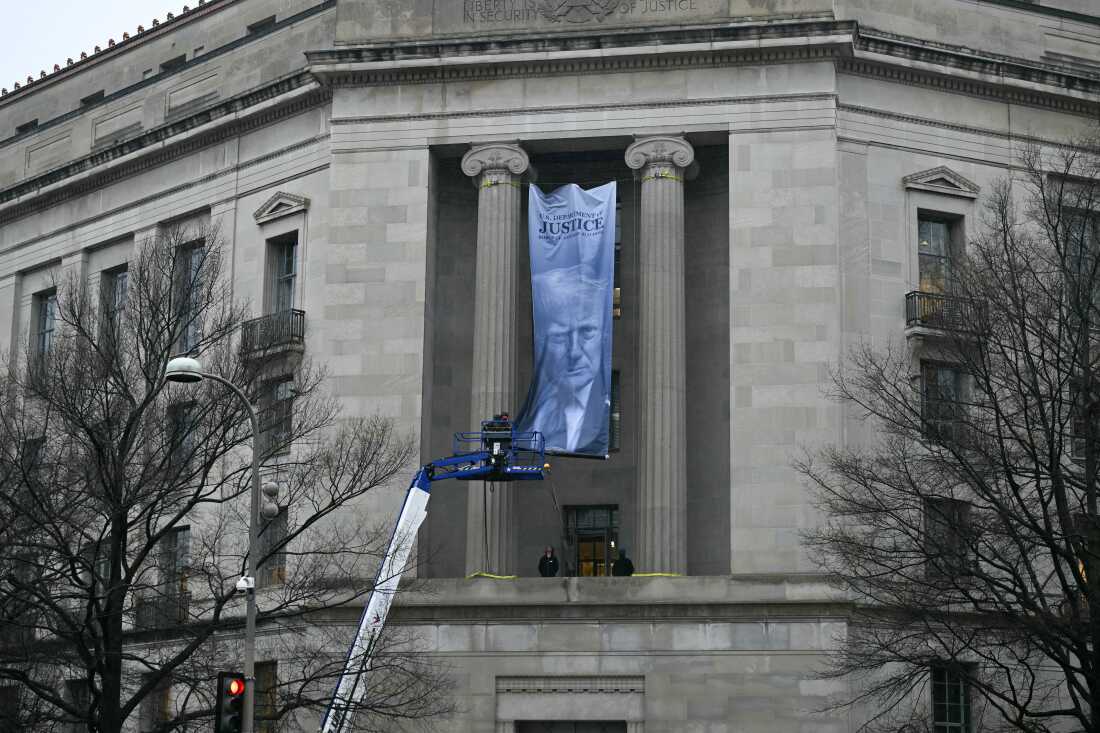 Workers on an aerial lift unfurl a new banner featuring President Donald Trump as it is installed on the façade of the US Department of Justice headquarters, Washington, DC, February 19.