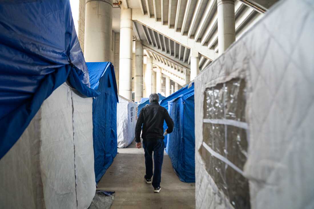 Mustafa Alloush walks between tents at a stadium where thousands of displaced are sleeping in Beirut after fleeing their homes during the invasion.