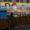Relatives of political prisoners hoist a banner with the Spanish word for "Democracy" outside the National Assembly emblazoned with images of former President Hugo Chavez and independence hero Simon Bolivar, in Caracas, Venezuela, Tuesday.
