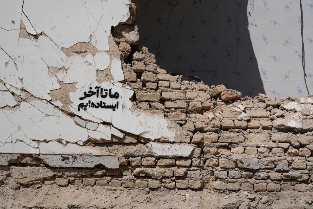 A residential building damaged by recent U.S.-Israeli strikes is seen with a sign on its wall that reads in Farsi: “We stand till the end,” in Fardis, west of Tehran, Iran, Friday, April 3, 2026. 