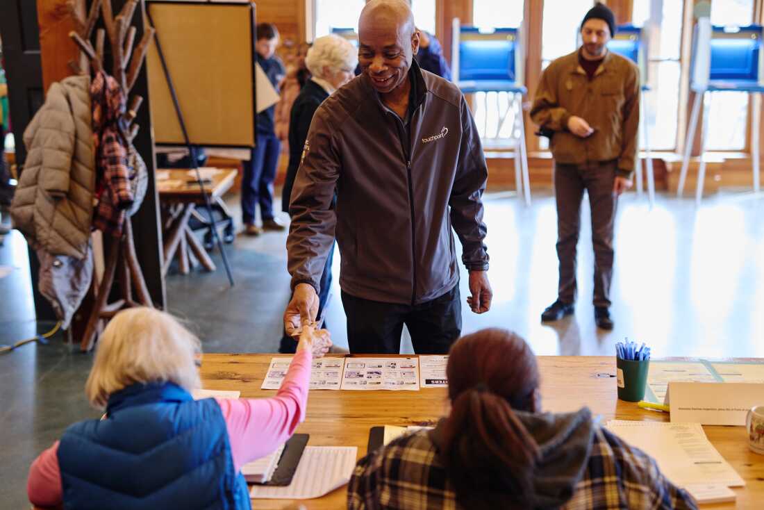 A voter hands over their license to a poll worker in a polling location at the Urban Ecology Center during statewide elections on April 1, 2025 in Waukesha, Wisc. The Justice Department is trying to get access to voter rolls in Wisconsin and many other states.