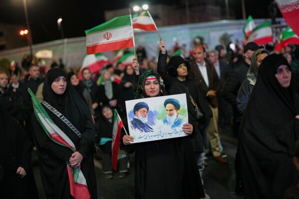 A woman holds a poster depicting the late Iran’s Supreme Leader Ayatollah Ali Khamenei, left, and the late revolutionary founder Ayatollah Ruhollah Khomeini during a pro-government gathering in a square in Tehran, Iran, Sunday, April 5, 2026. (AP Photo/Francisco Seco)