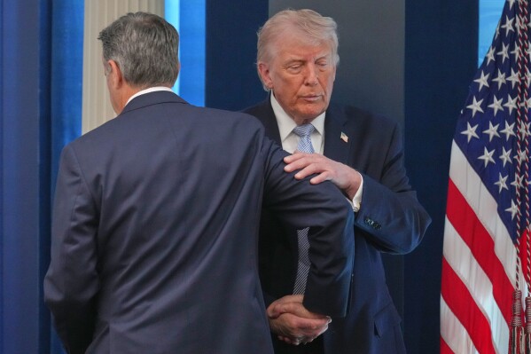 President Donald Trump shakes hands with CIA Director John Ratcliffe as they speak with reporters in the James Brady Press Briefing Room at the White House, Monday, April 6, 2026, in Washington. (AP Photo/Mark Schiefelbein)