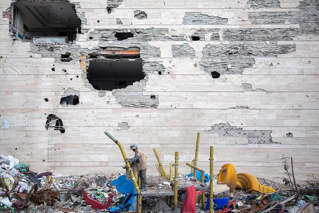 People walk among buildings destroyed in a joint attack by Israel and the United States on April 6, 2026, in Tehran, Iran.