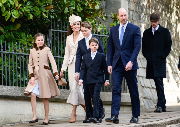 From left, Princess Charlotte of Wales, Catherine, Princess of Wales, Prince George of Wales, Prince Louis of Wales and Prince William, Prince of Wales walk outside on a sidewalk