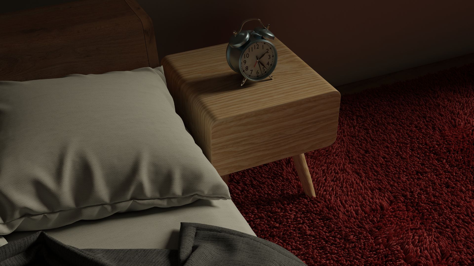 A shot of part of a bed and a bedstand with an alarm clock on it. The room is dark.