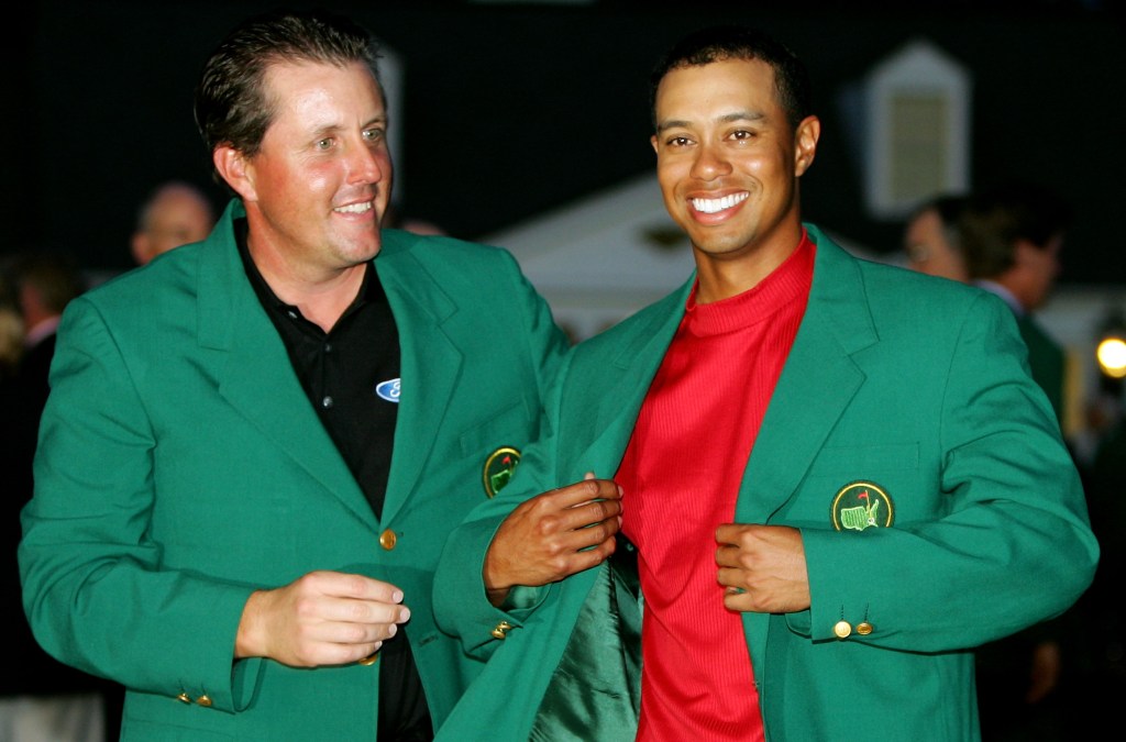 Tiger Woods smiles as he is presented with the green jacket by Phil Mickelson after Woods won The Masters at the Augusta National Golf Club on April 10, 2005 in Augusta, Georgia.