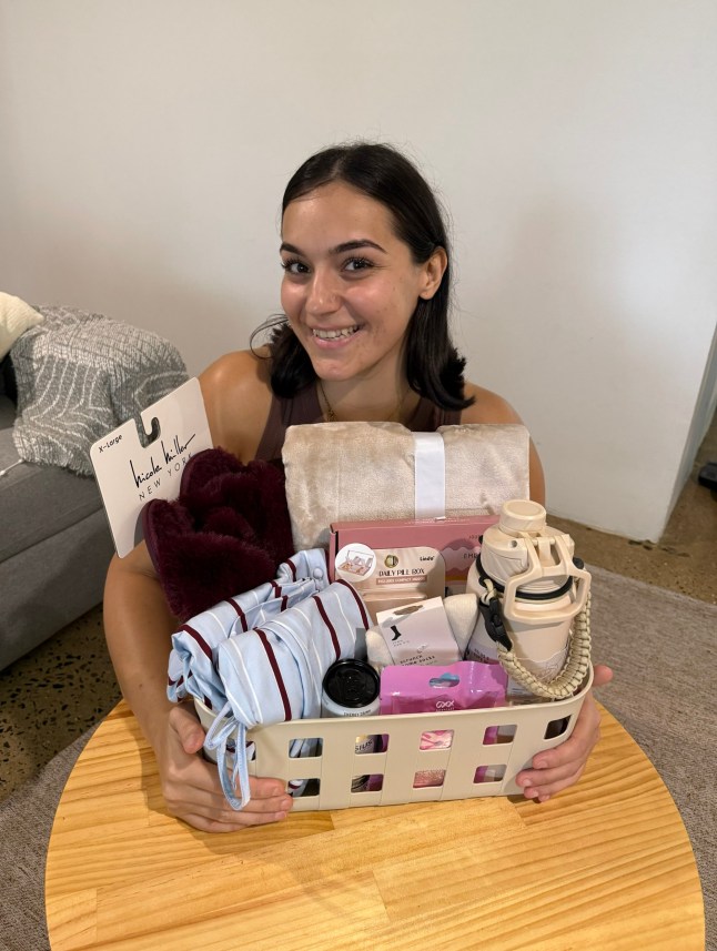 Sumbul Ari, who was diagnosed with cancer at the age of 26, smiles while holding a box of products for work.