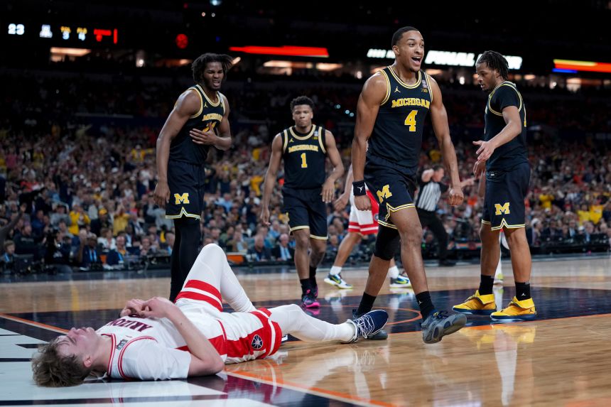 Michigan guard Nimari Burnett (No. 4) celebrates a basket near a downed Arizona player in the first half.