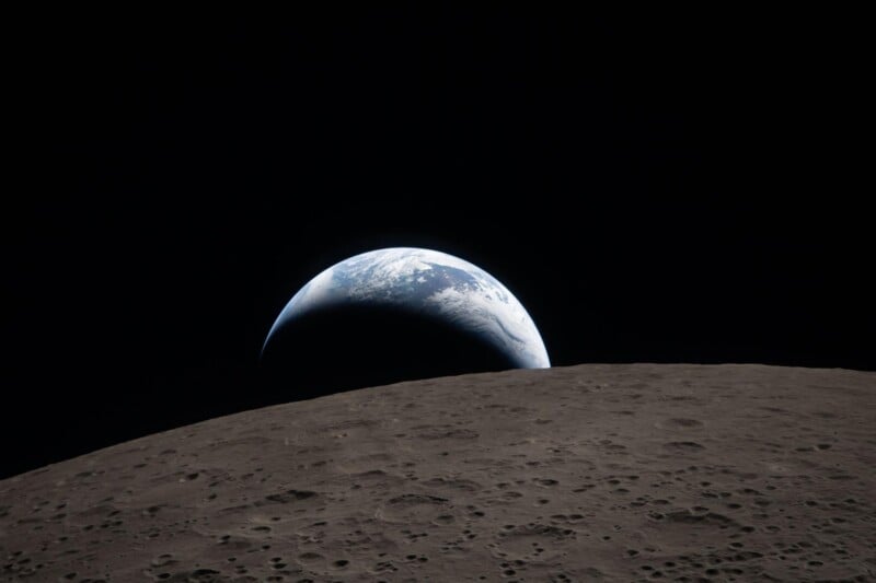 The Earth appears partially illuminated, rising above the gray, cratered surface of the Moon against the blackness of space.