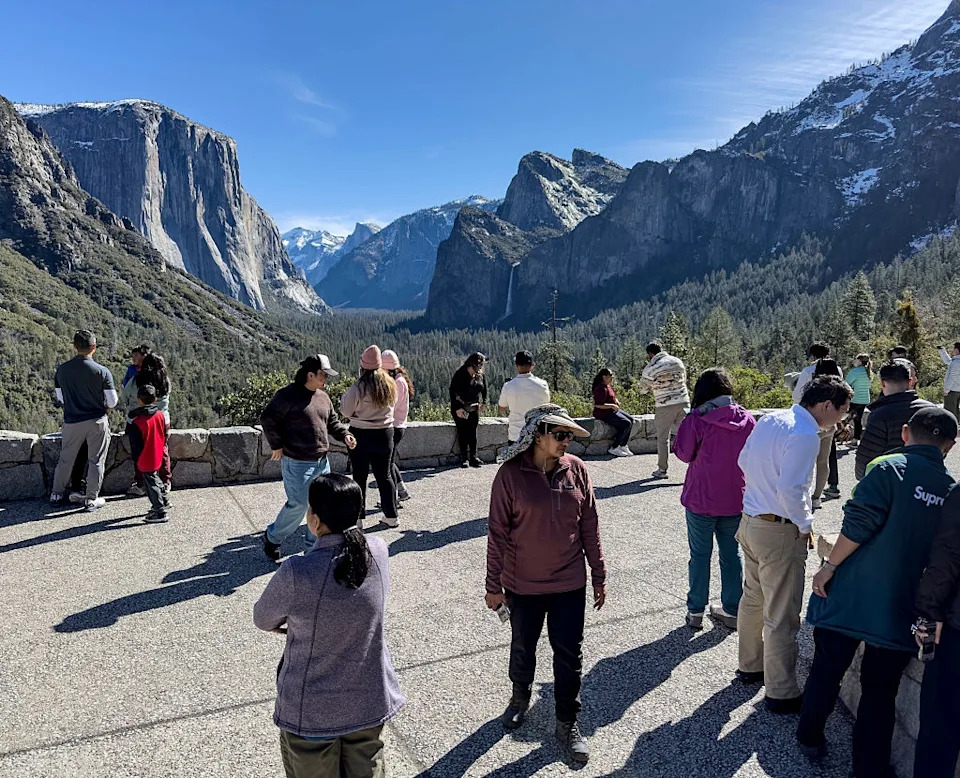 People enjoying a scenic view of mountains and a valley observed from a lookout point