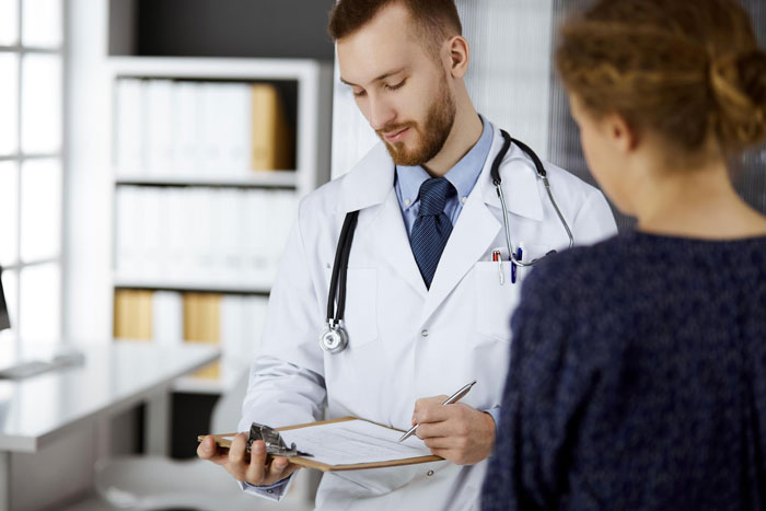 Young female patient consulting doctor in a medical office after imagining things and hearing voices before ER visit