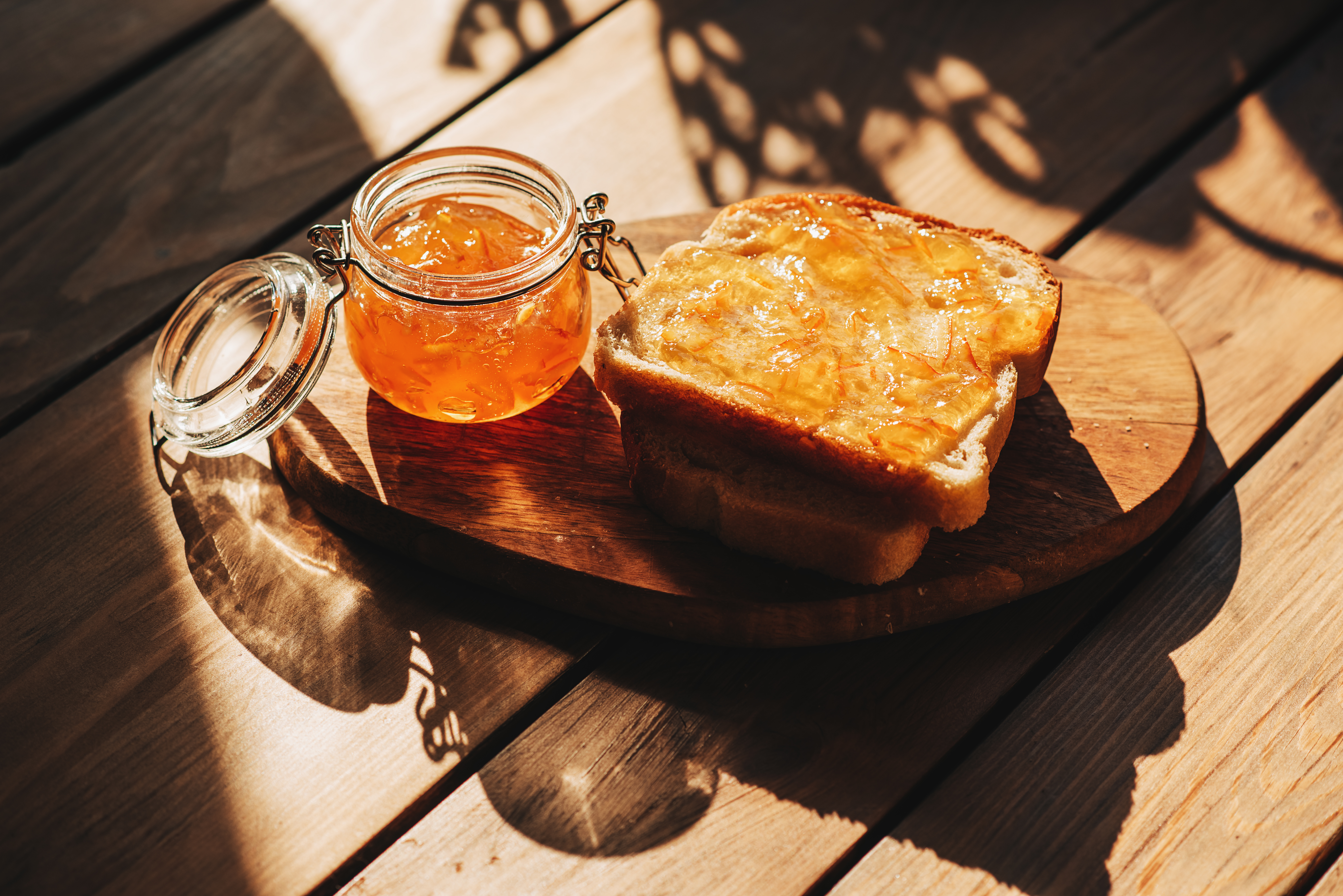 A jar of orange marmalade beside a slice of toast