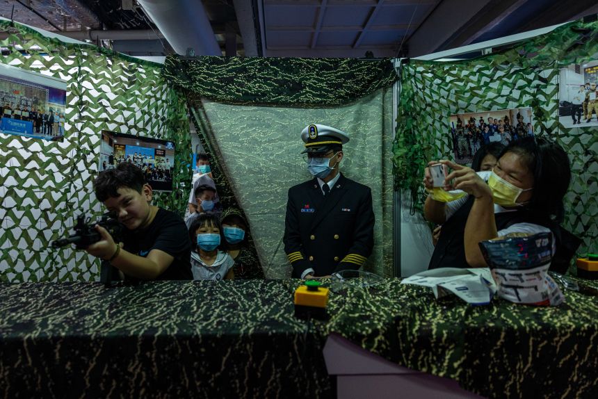 A child practices an airsoft gun on a warship inside a Taiwan's Navy camp during a recruiting event at Xinbin Port in Kaohsiung, Taiwan, on March 11, 2023.