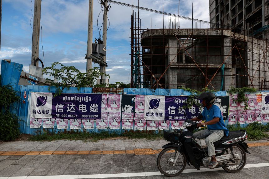 A motorbike rides past an unfinished building in Sihanoukville, Cambodia, on July 1, 2024.