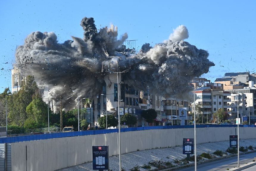 Smoke and debris fly around at the site of an Israeli strike that targeted a building adjacent to the highway that leads to Beirut's international airport on Tuesday.