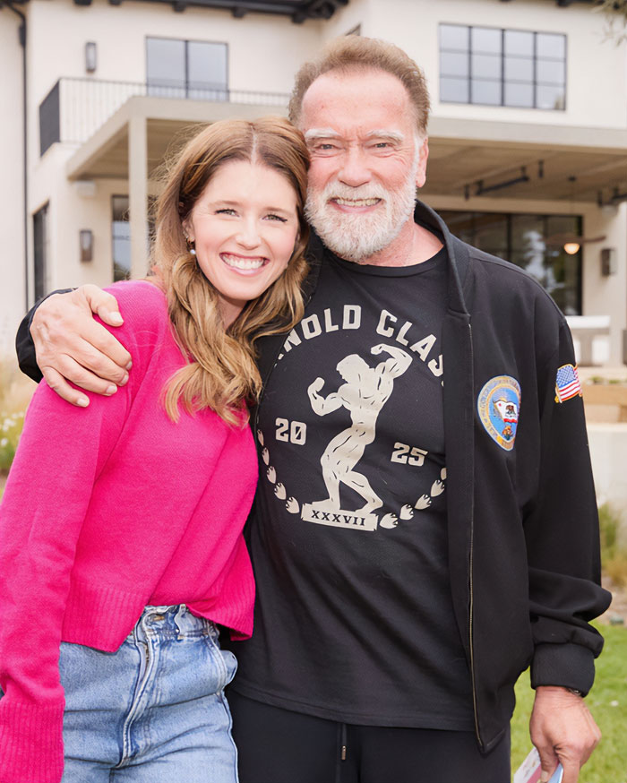 Katherine Schwarzenegger smiling and posing outdoors with Arnold Schwarzenegger, highlighting nepo baby celebrity discussions.