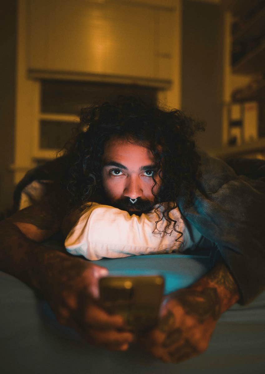man lying in bed on his phone struggling to maintain boundaries