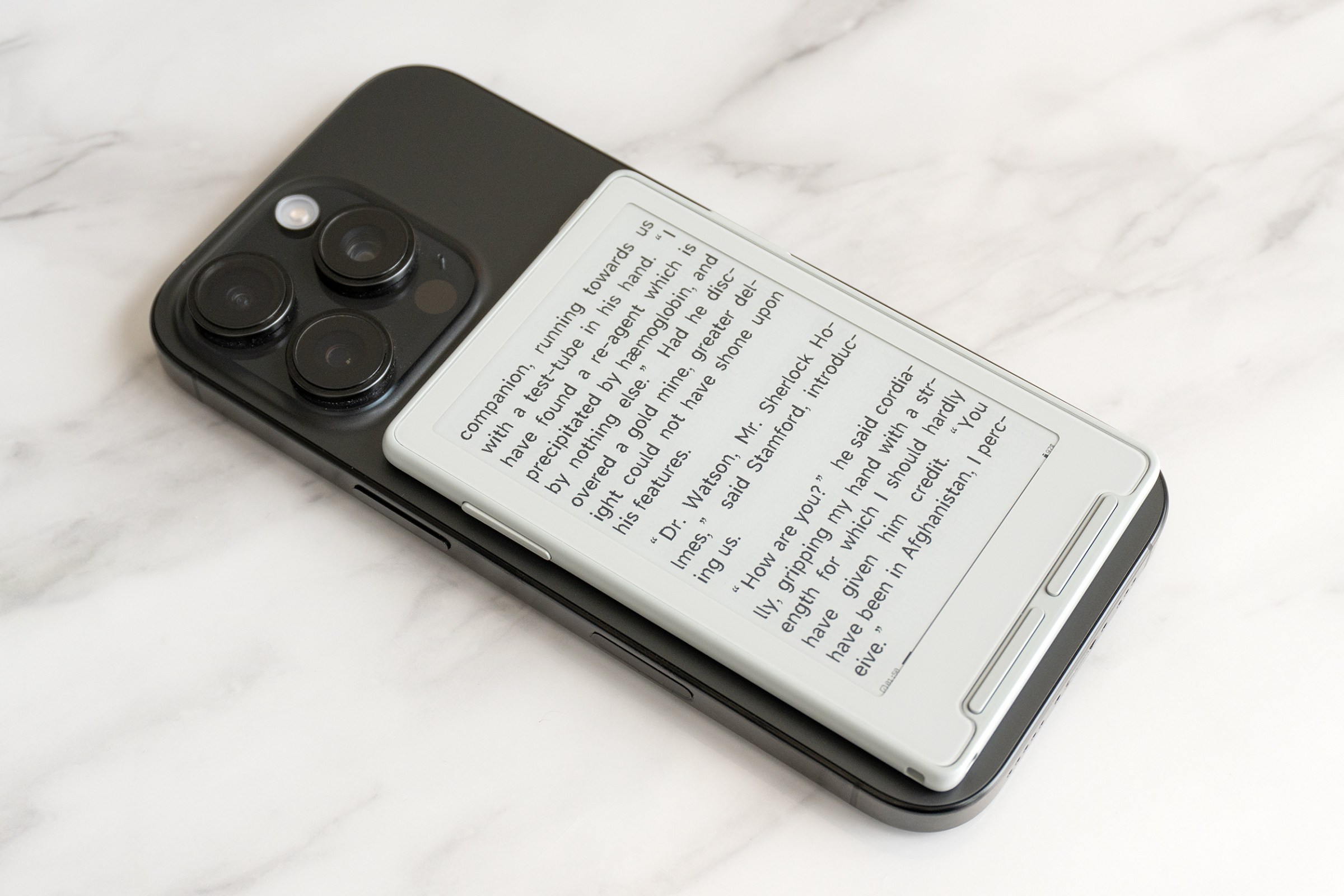 The Xteink X3 e-reader attached to the back of an iPhone 16 Pro.